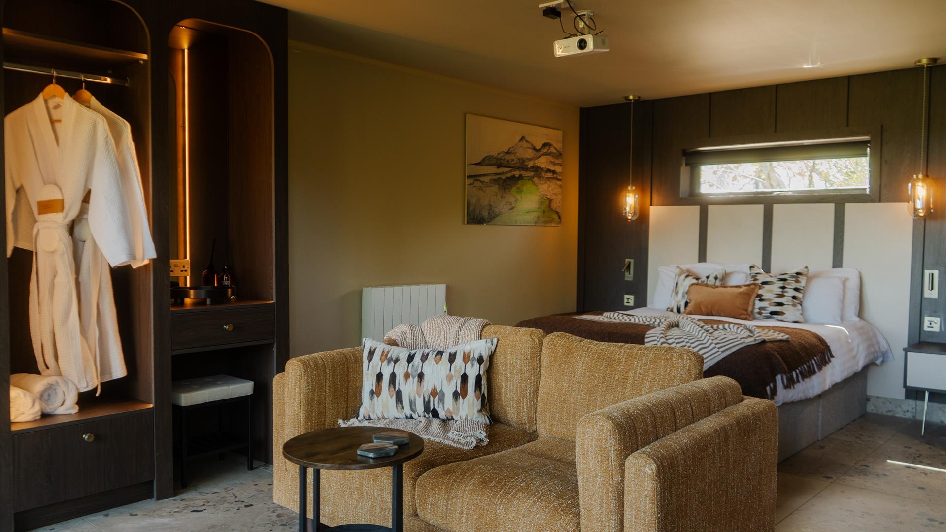 Luxury suite with bed, sofa and robe hanging in open wardrobe
