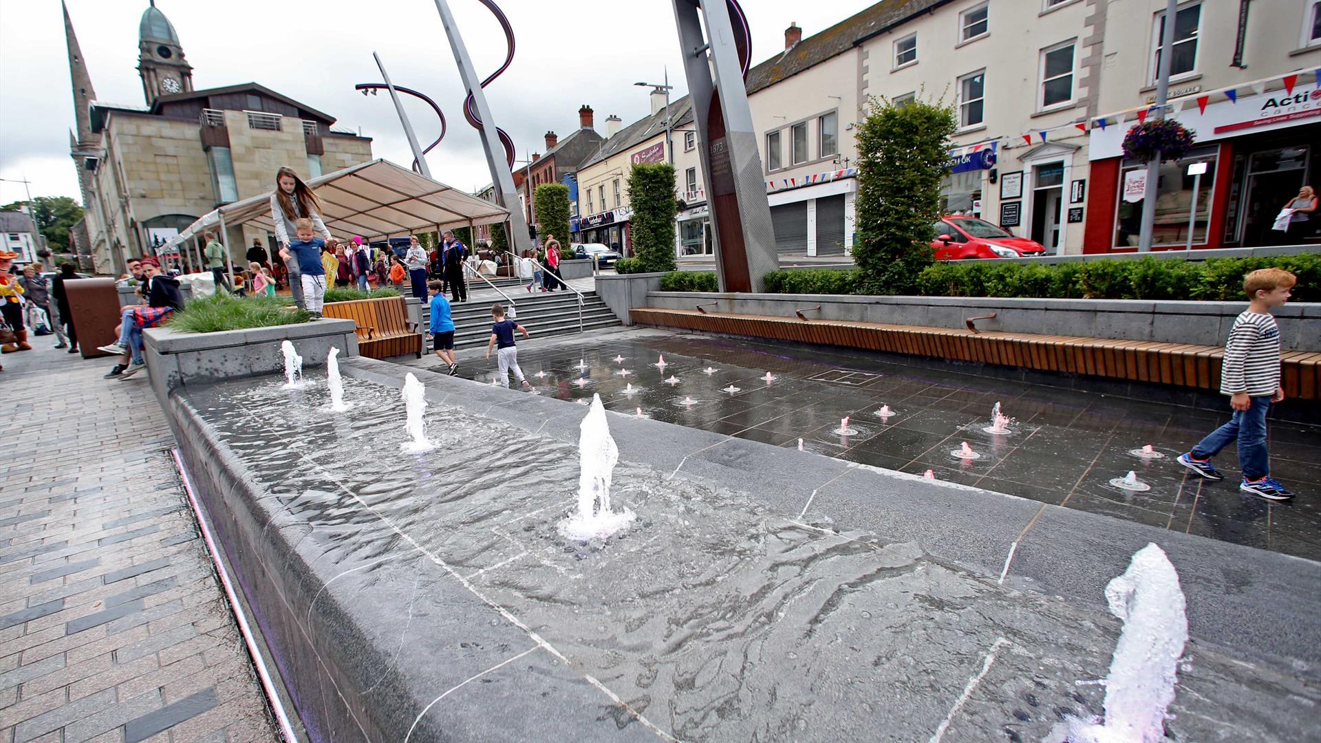 Water fountains in Market Square with child playing with people in the background