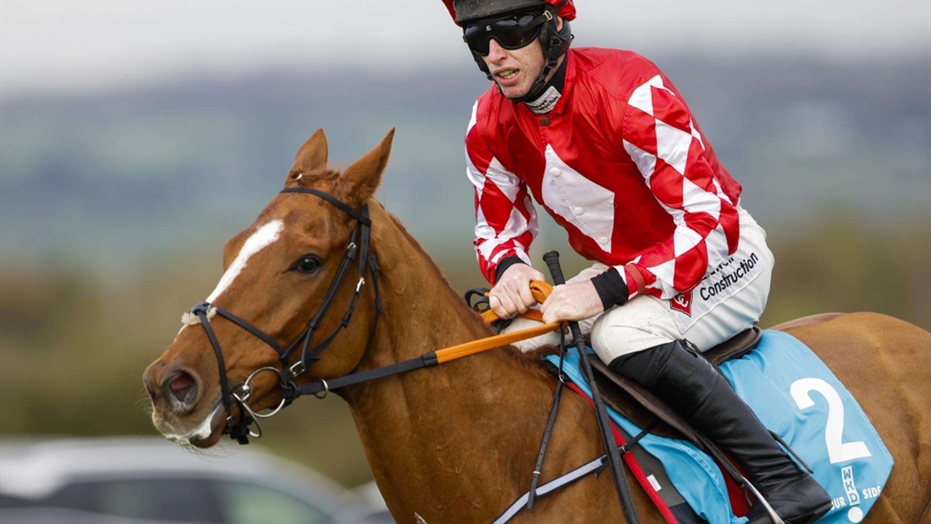 Jockey riding horse wearing red and white top
