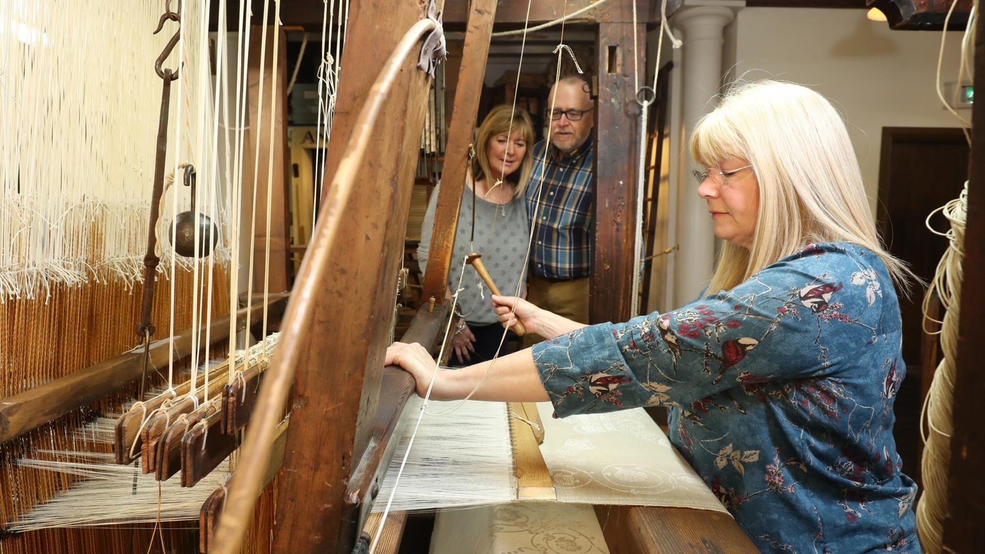 Couple watching a lady using the loom