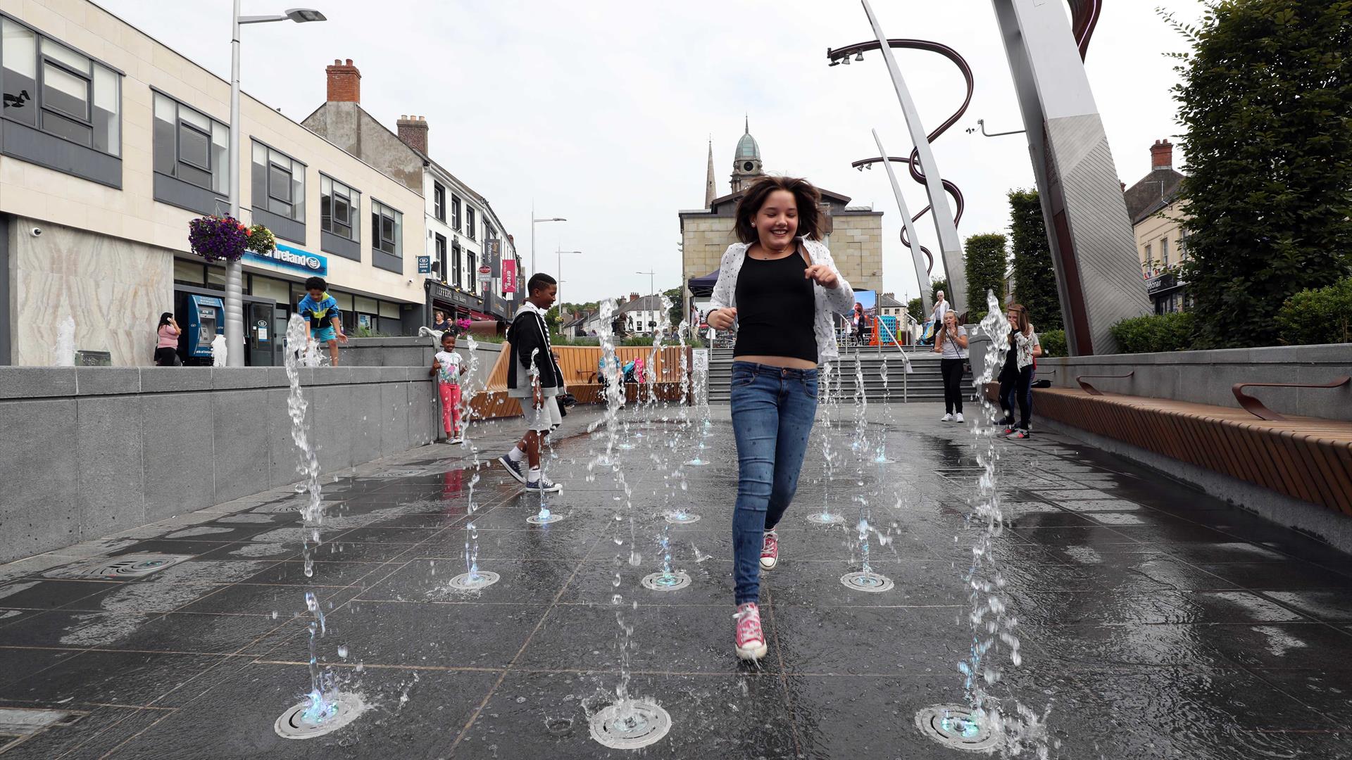 Girl running through fountains in Market Square, Lisburn