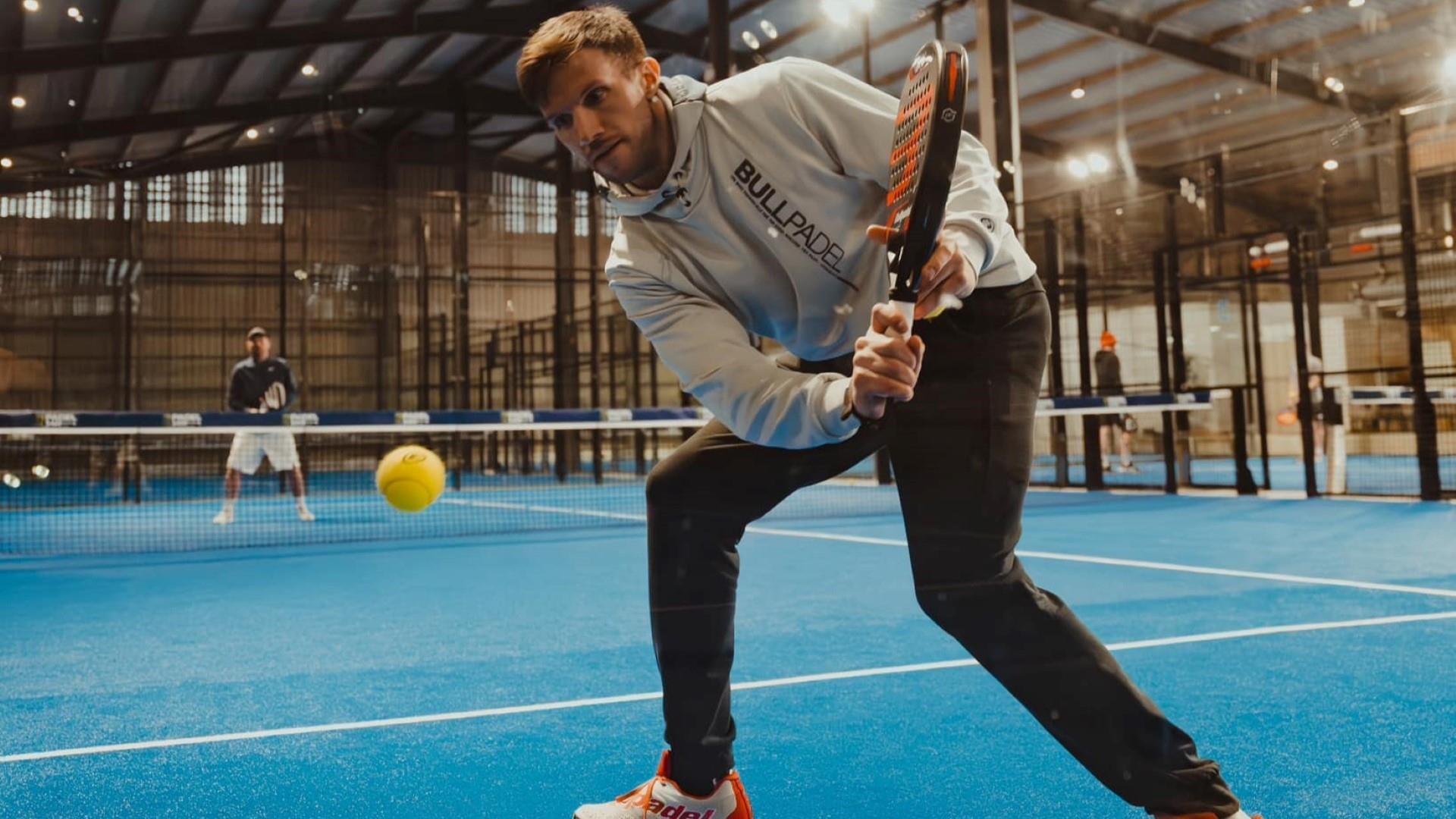 Image shows two individuals playing Padel Tennis on blue court.