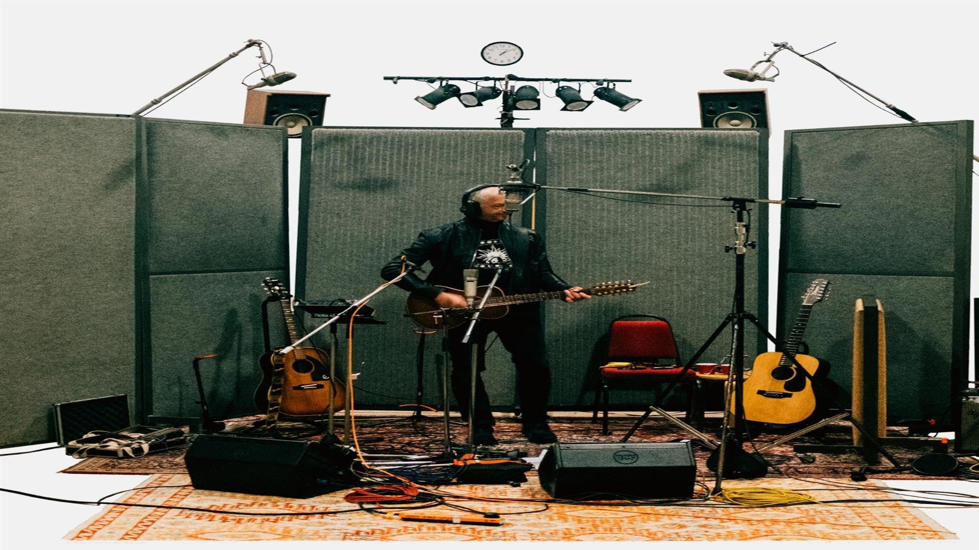 Image is of musician Andy White playing guitar in a recording studio