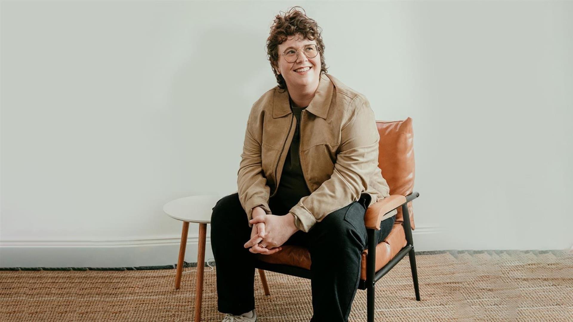 Image is of Irish comedienne Emer Maguire sitting on chair and smiling