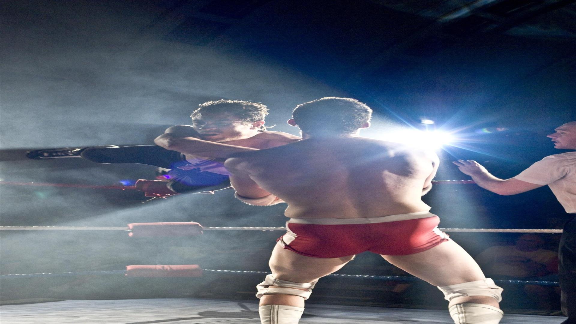 Two wrestlers on stage with a referee