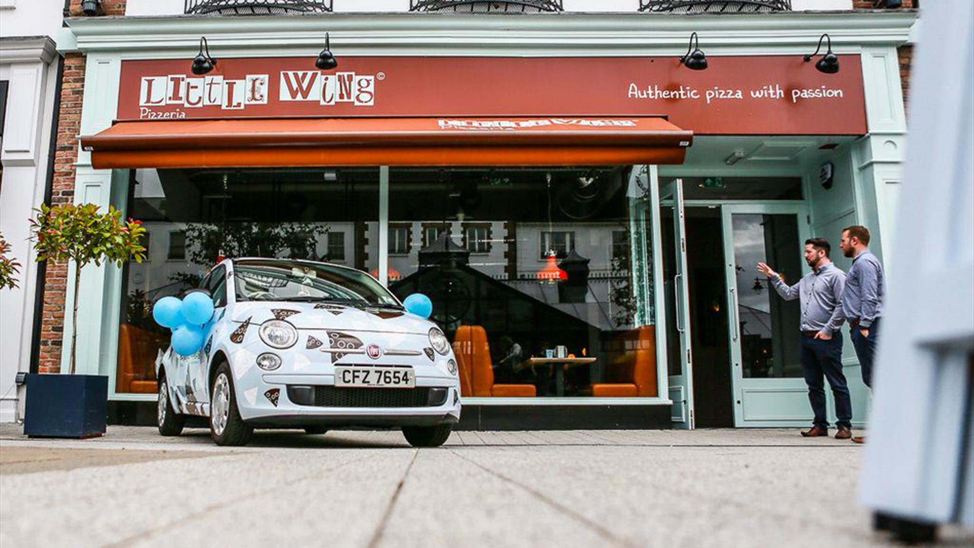 Shop front of Little WIng pizzeria with a branded promotional car out the front.