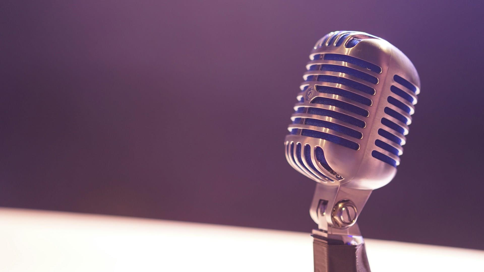 Picture of a silver coloured microphone with a purple background