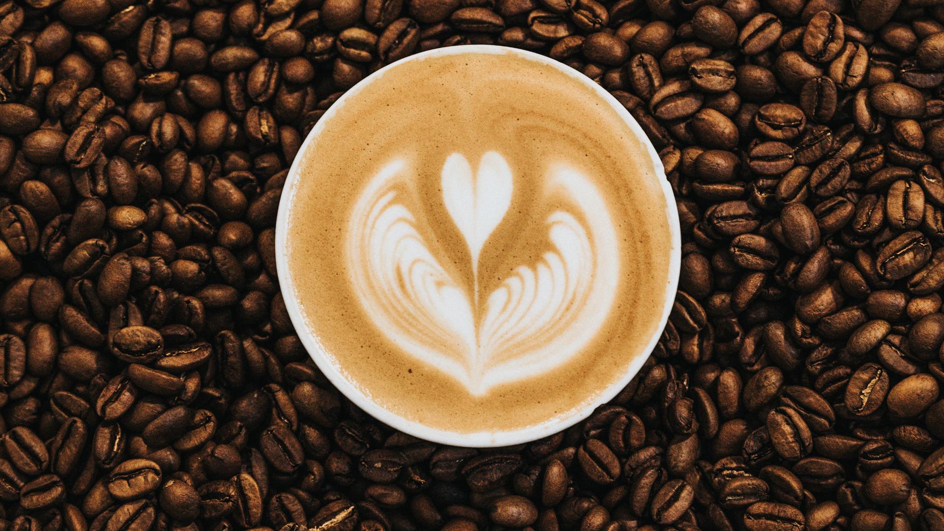 Image shows coffee beans and cup of coffee sitting in the middle.