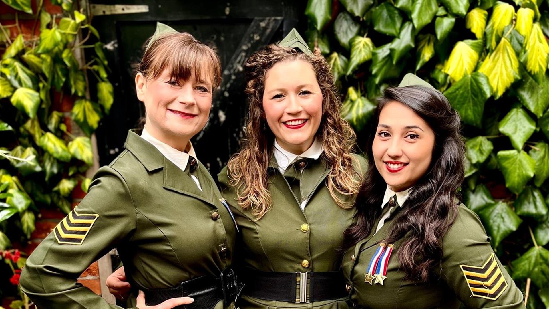 Image shows 3 swing girls dressed in green military style uniform