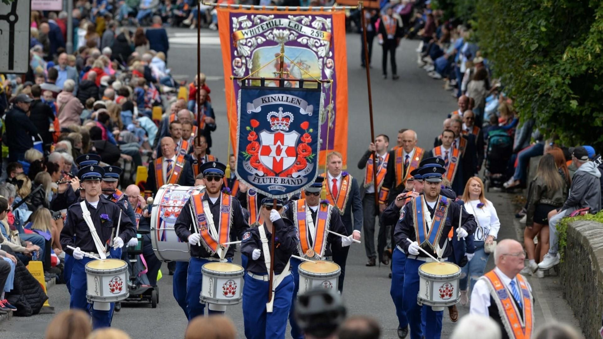 Image is of a Twelfth of July parade with spectators