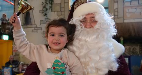 Pictured is Santa Claus with a Child ringing a bell.