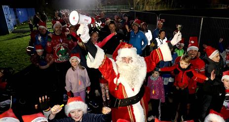Picture of Santa Clause and surrounding children 
 wearing Santa hats.