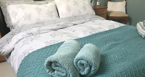 Image shows double bed with rolled up towels at the bottom