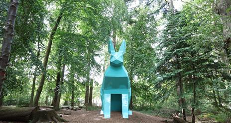 An image of Peep the Hare part of the digital sculpture trail, the hare is teal and is located in the forest park.