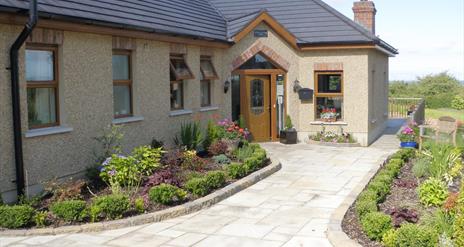 Image shows front of property with walk way and garden