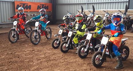 Image shows row of children on mini motorcycles