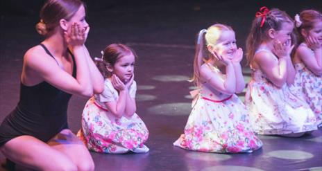 Young girls on stage with dance teacher