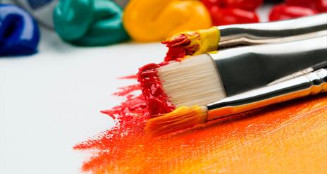 Paint brushes with pain on them and blogs of paints in the background