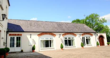 Image shows front of the property facing onto gravel drive/courtyard