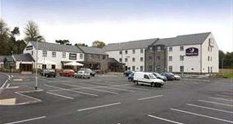 Image shows front of hotel and car parking spaces