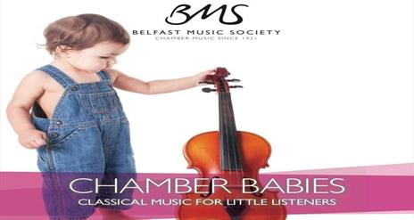 Image shows baby with blue dungarees and holding a violin.