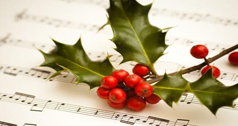 Image shows holly with berries and music sheet