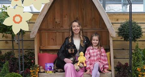 Image of Woman, girl and Dog sitting with Easter treats around them.