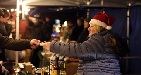 Lady with Santa hat selling at a stall at Christmas Market