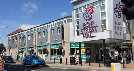 Image shows entrance to Bow Street Mall with visitors exiting the mall and cars driving by