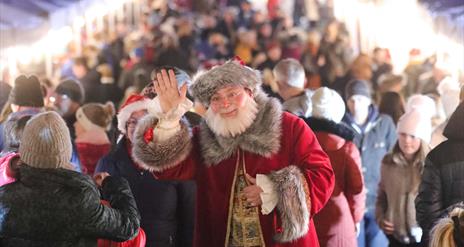 Santa waving with people shopping at Market behind him