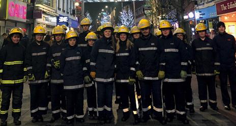 Fire Fighters standing in a row under the Christmas Lights in Bow Street