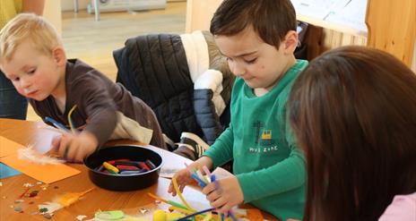 Image is of young children at a craft session in the Irish Linen Centre and Lisburn Museum