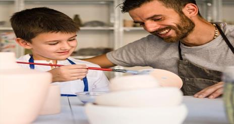 Image shows father and painting pottery.
