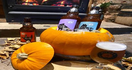 Image is of a pumpkin with beers from Hilden Brewery sitting inside