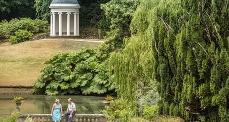 Picture of a couple sitting on a bridge with Lady Alice's Temple in the background
