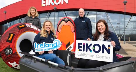 Image is of the organisers of the Ireland on the Water Expo in a dinghy and holding a surfboard outside the Eikon Exhibition Centre