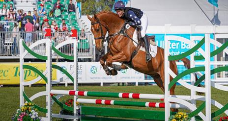 Man on horse jumping over a fence