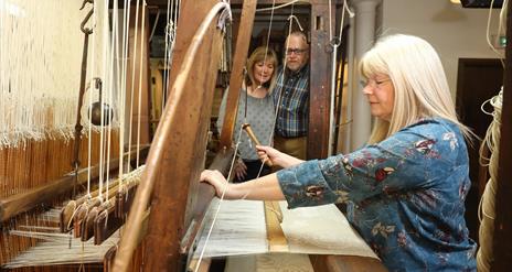 Couple watching a lady using the loom