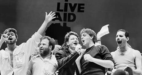 Image is of various rock stars performing on stage at Live Aid Wembley Arena London