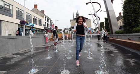 Girl running through fountains in Market Square, Lisburn