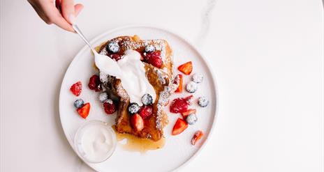 Image is of French toast, strawberries and cream at Mimi's Speciality Coffee
