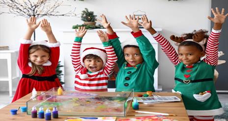 Image is of children dressed in Christmas outfits