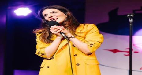 Image is of comedienne Wafa Daldoul on stage performing