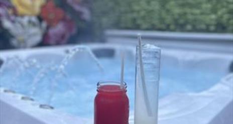 Image is of a hot tub with a glass drink sitting on the side