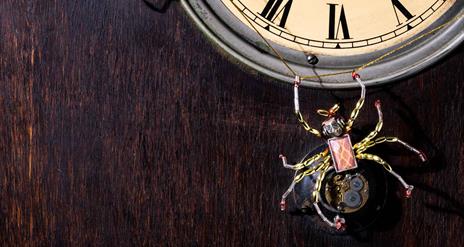 Picture of a old fashioned clock with two spiders on it and a web just below