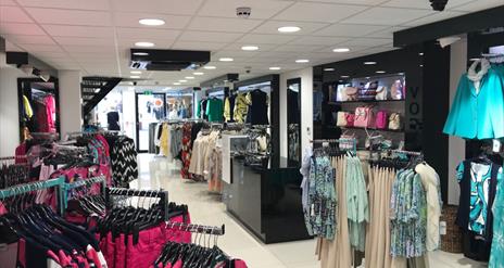 Inside Vogue Lisburn, clothing racks and handbags