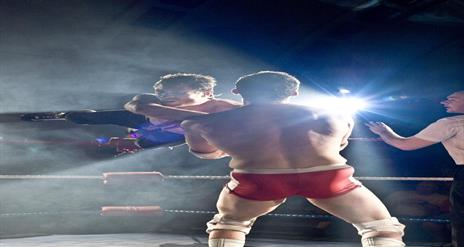 Two wrestlers on stage with a referee