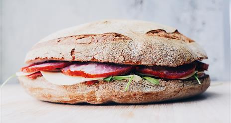 Image shows a ciabatta sandwich with ham and lettuce