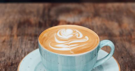 Image shows cup & saucer with latte coffee