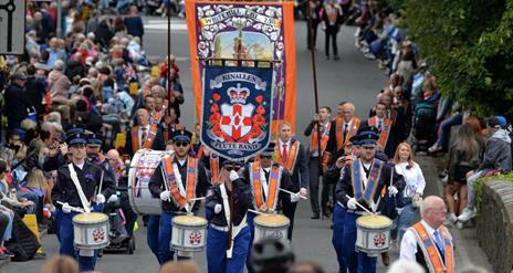Image is of a Twelfth of July parade with spectators
